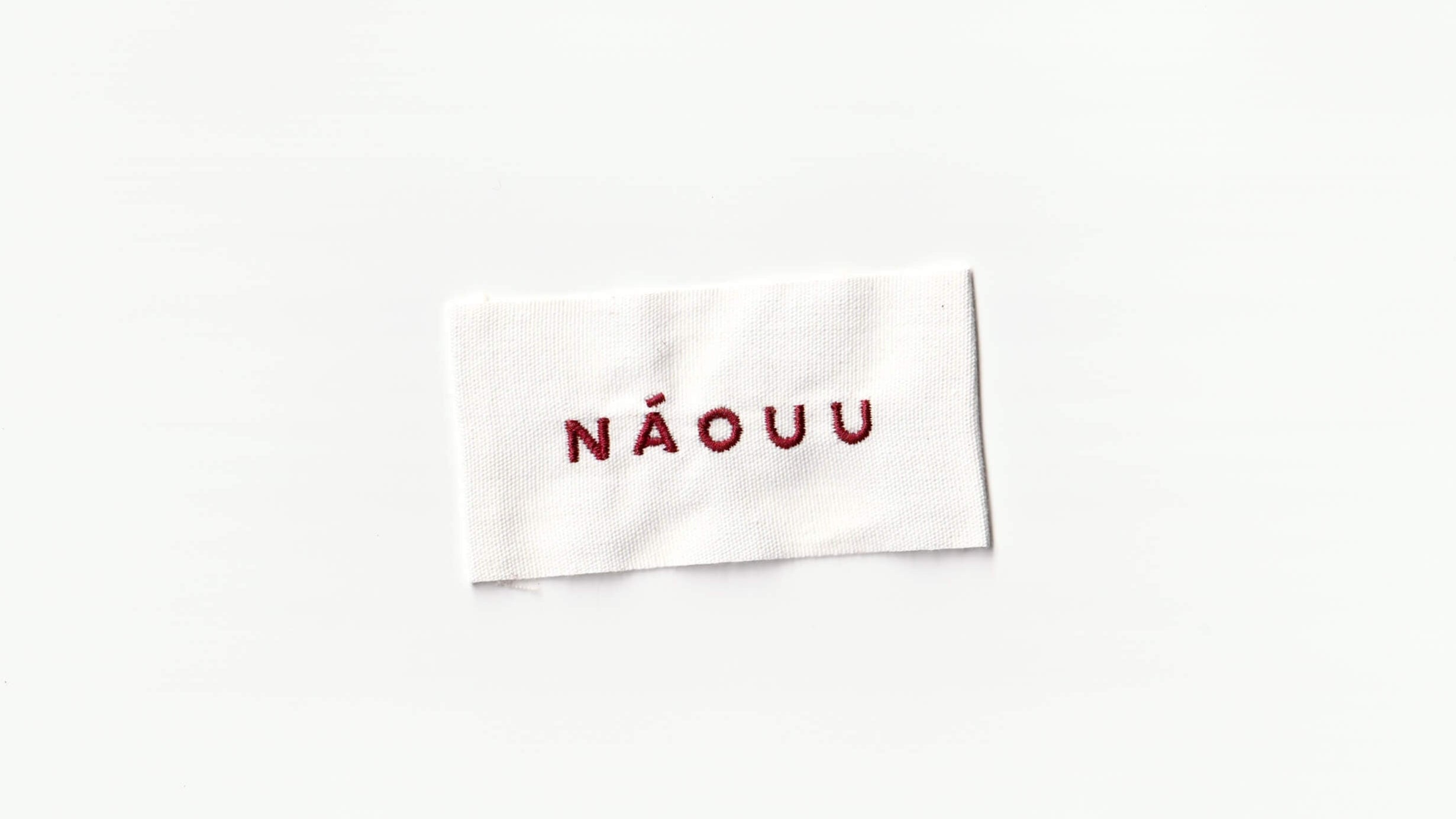 Premium off white clothing tag with red embroidery with "NÁOUU" logo